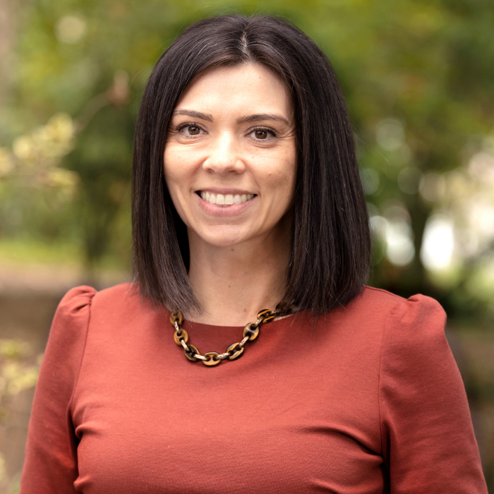 A headshot of Alicia Stevenson with green foliage in the background.